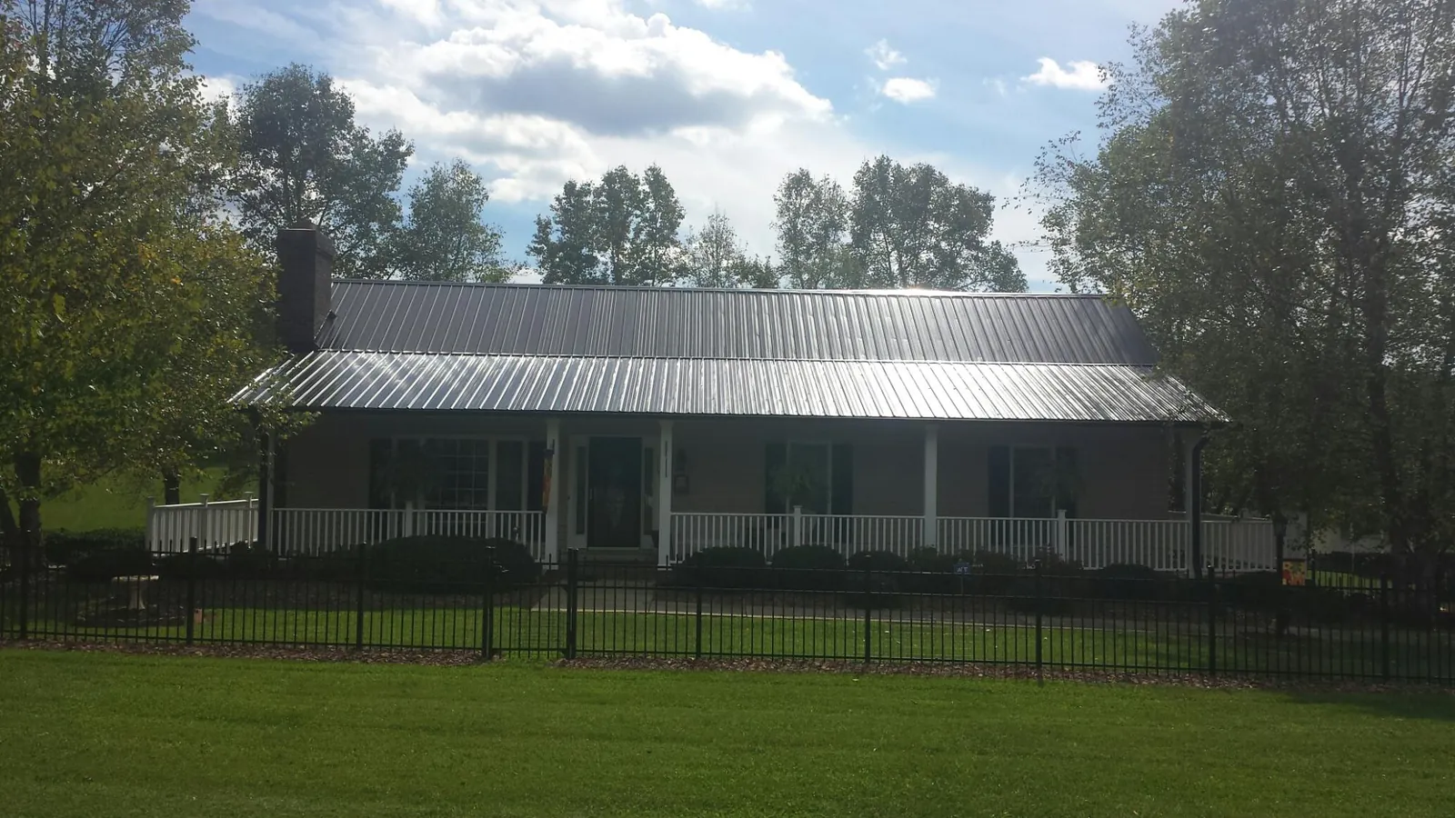 Gray metal roof on a brick ranch with a full width front porch — Gutter Guard Installation work by our crew in Strasburg