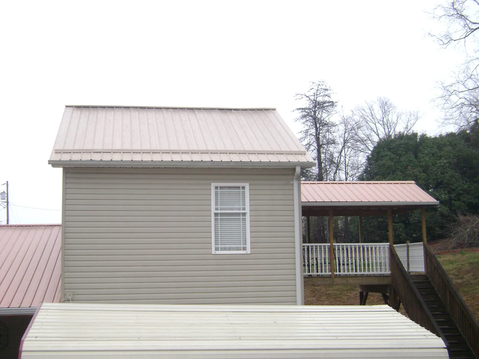 Tan metal roofs on a two story addition and attached porch, from a Roof Replacement job in Strasburg